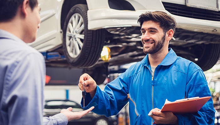 Service technician handing keys back to customer - Finnegan Buick GMC in Rosenberg TX
